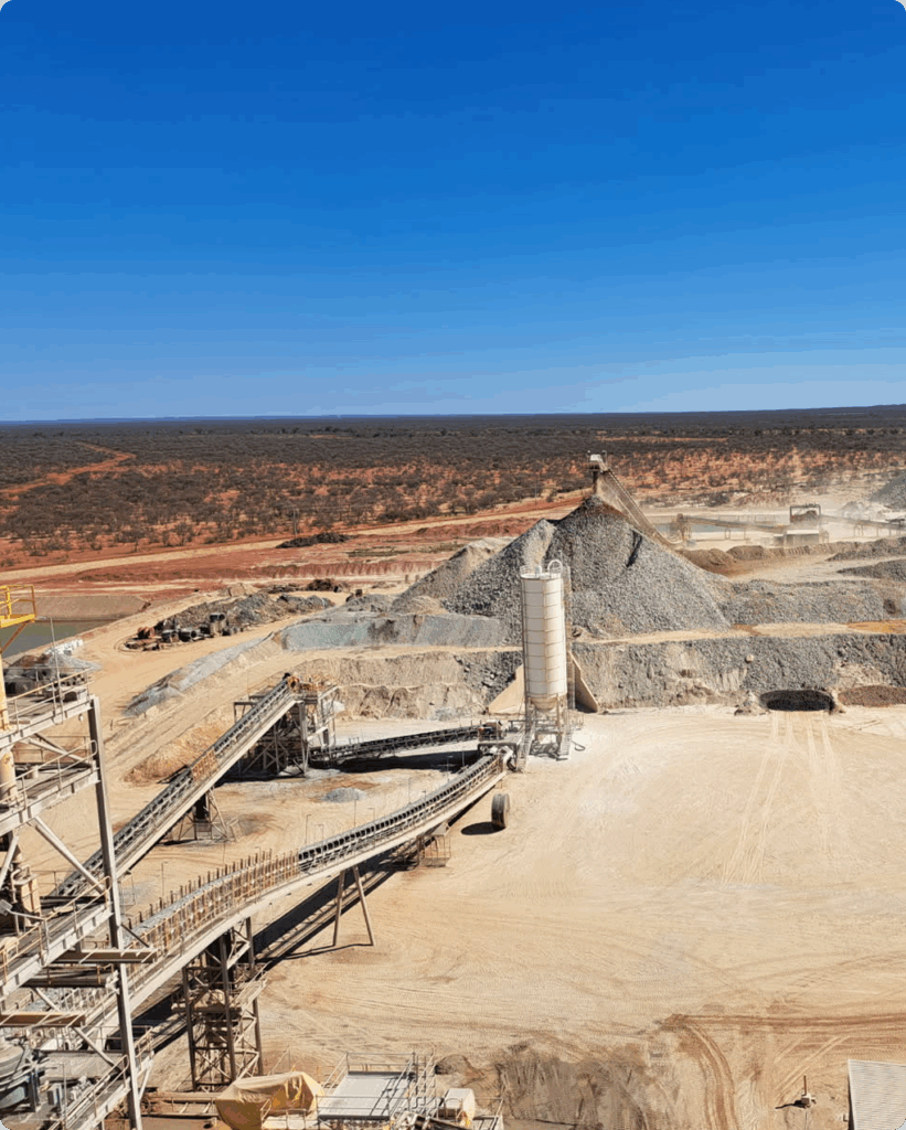 A view of an open pit mine with a conveyor belt and truck, illustrating electrical tagging services used in the mining industry