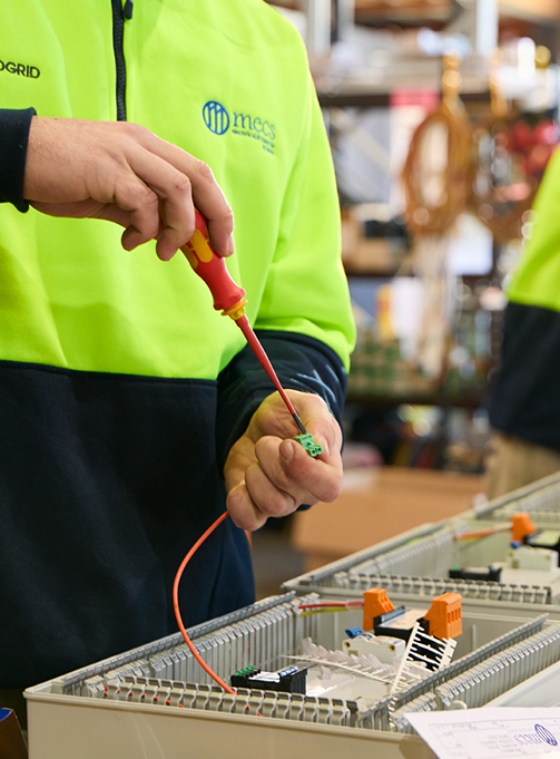 A technician in green vest performing electrical repairs and maintenance, providing reliable electrical services near me