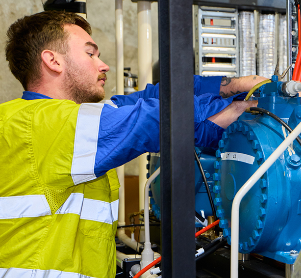 A technician in a safety vest operates equipment in a workshop, providing reliable electrical services near me
