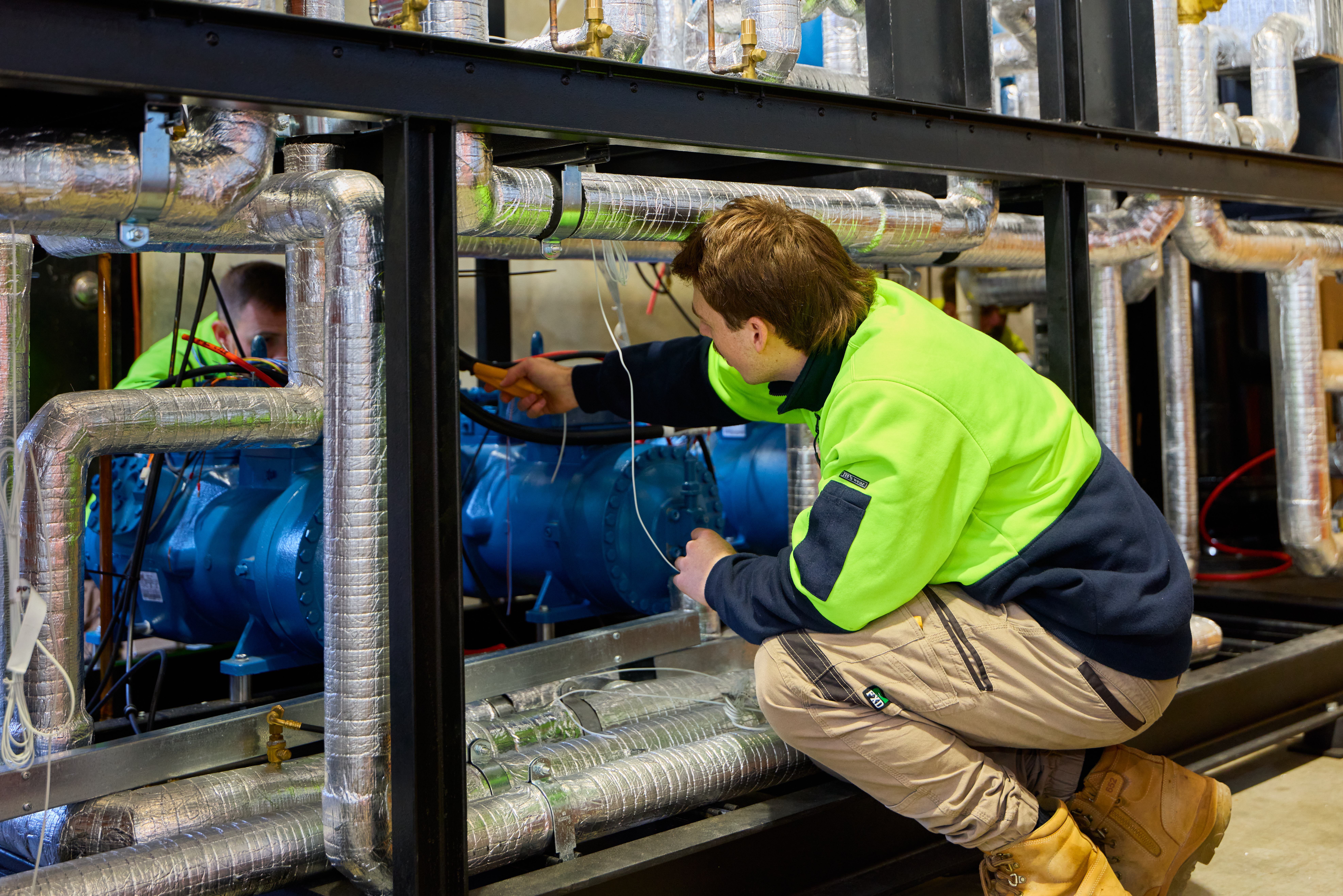Worker in green and blue jacket operating machinery as part of labour hire services of Progrid on an industrial site