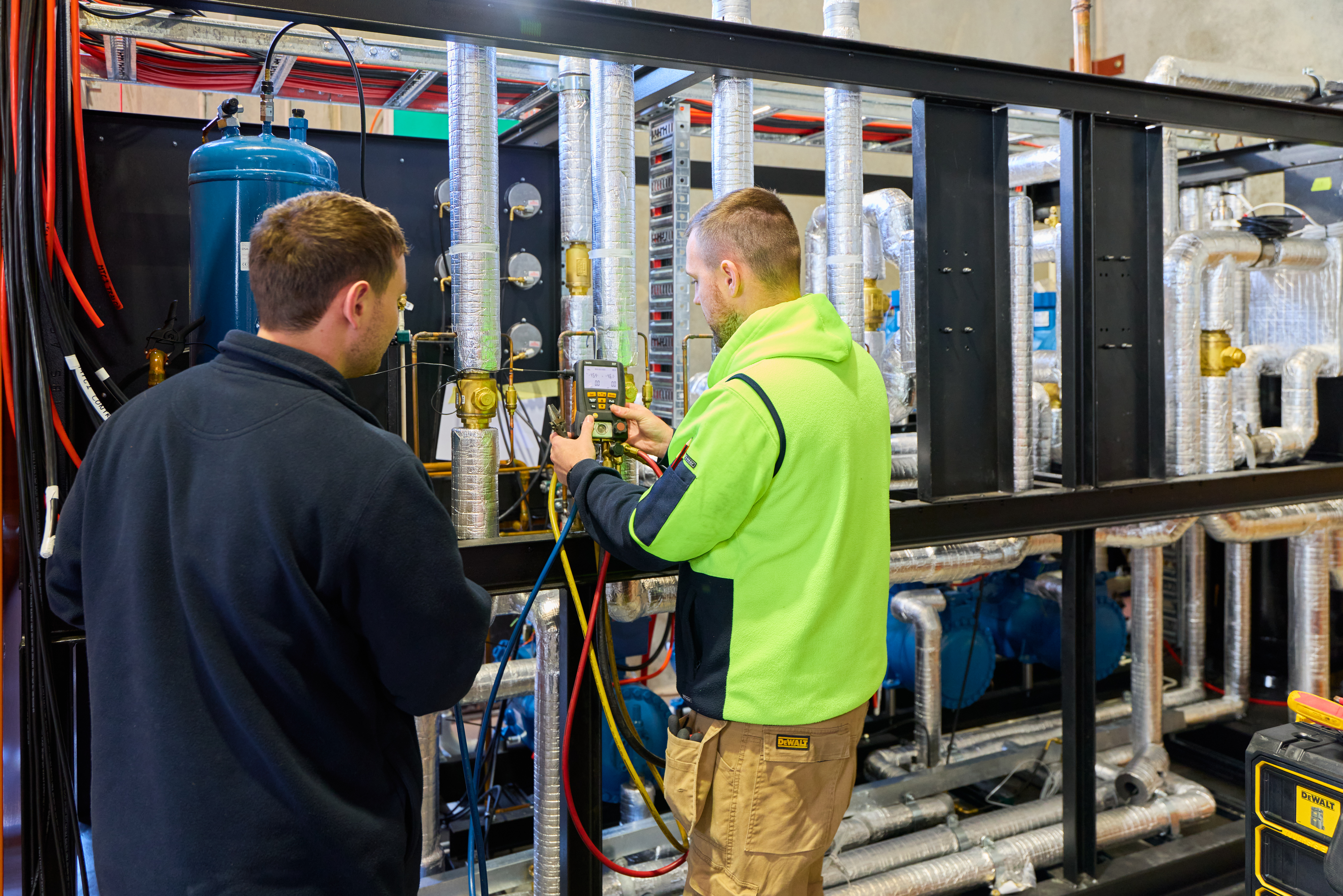 Two men wearing jackets operate a machine, showcasing labour hire services in action