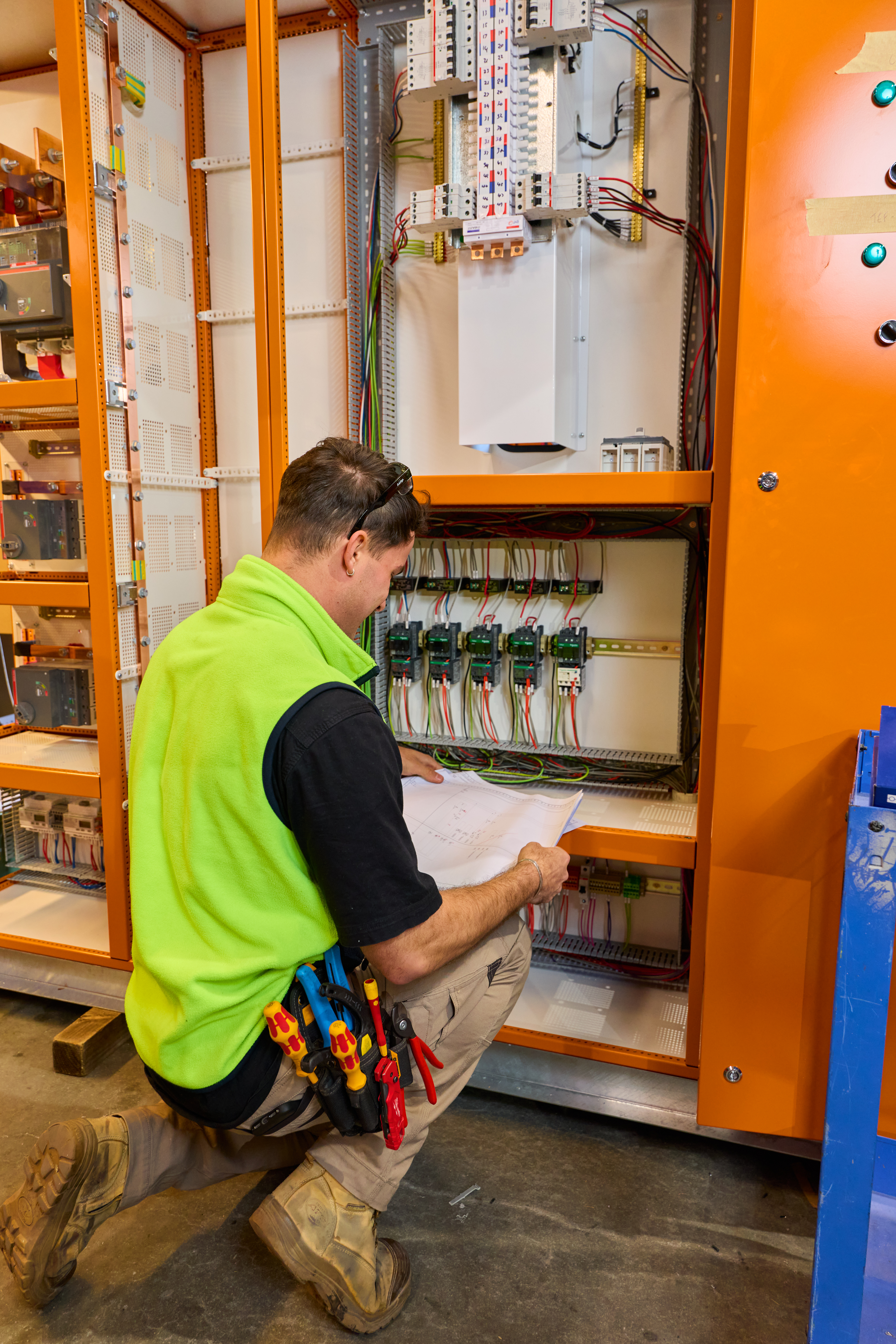 Technician in green vest repairing electrical equipment as part of labour hire services of Progrid on-site workforce support